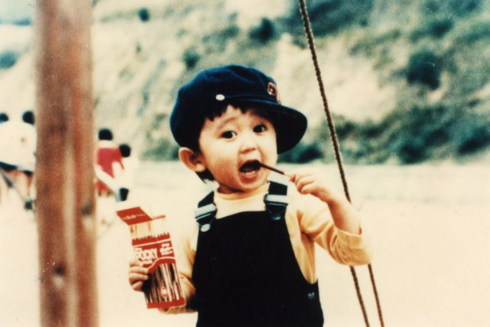 ポッキーを食べる子どものころの有吉弘行さん
