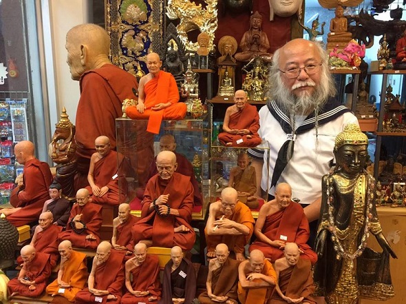 お土産屋さんの中、タイの有名な僧侶の像に囲まれるセーラー服おじさん……意外と馴染んでいる