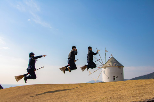 携帯電話を見ながらホウキに乗る男