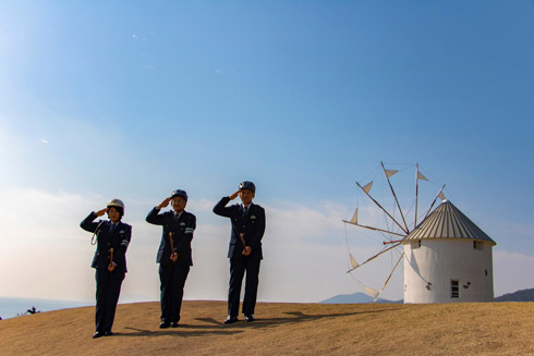 ヘルメットをかぶって敬礼するホウキ乗りたち