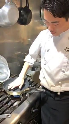 フライパンに手を当てるシェフ