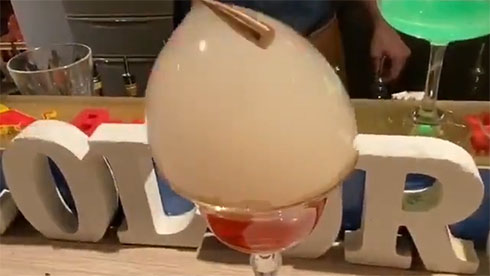 グラスの上に大きなシャボン玉がありスプーンで触っている