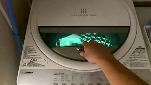 洗濯機のふたをあけるところ。中が光っている