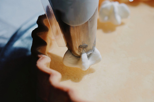 透明なレモンタルトに生クリームをしぼる様子