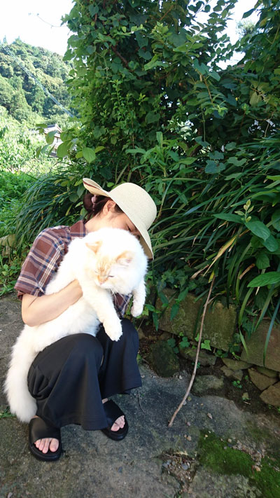 座る飼い主さんに抱っこされるハクさん