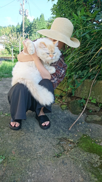 座る飼い主さんに抱っこされて正面を向くハクさん