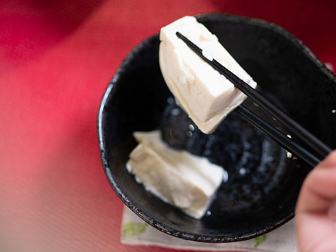 三角の湯豆腐を箸で持ち上げた