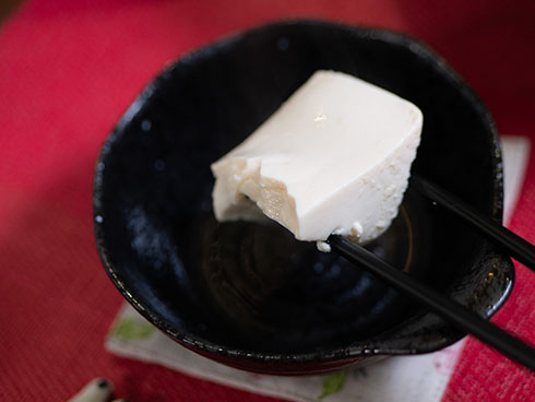 三角の湯豆腐を箸で持ち上げた