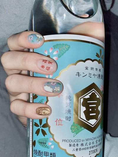 焼酎ネイルをして焼酎を持っている