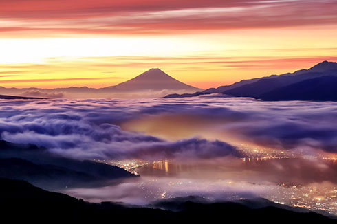 朝焼けの富士の麓に広がる雲海の下に街の灯り