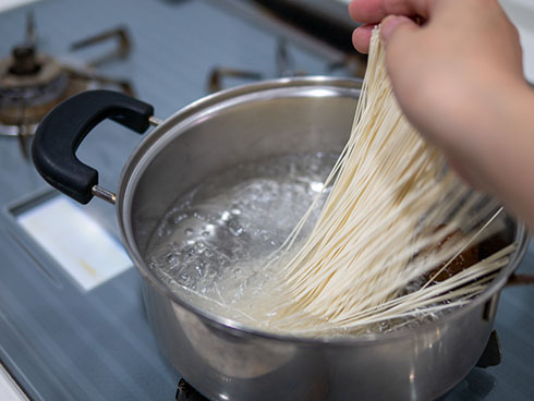 そうめんを鍋に入れるところ