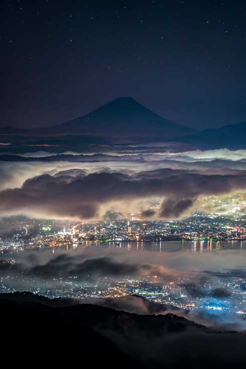 雲の上から街を見守る 富士山 写真