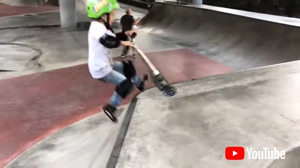 Little Kid Shows Tricks On Scooter While Practicing For Competition In Skatepark