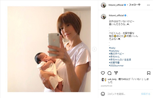 子どもを抱きかかえながらスマホをチェックするhitomi