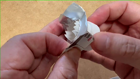 紙パックのふたがアルミを切る様子