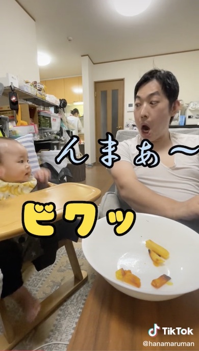 クセの強い顔で赤ちゃんをあやす父の写真