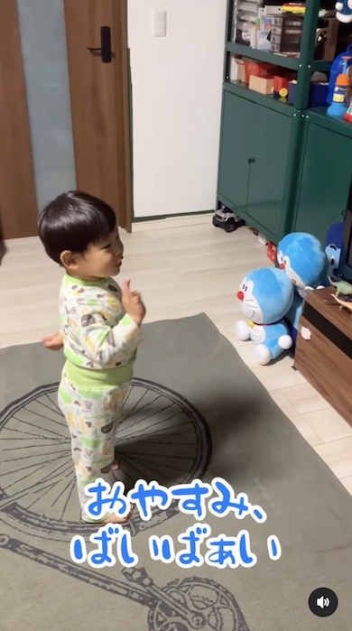 本やおもちゃにおやすみを告げる男の子の写真