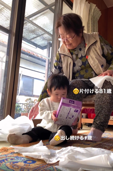 ティッシュで遊ぶ赤ちゃんを見守るひいおばあちゃん