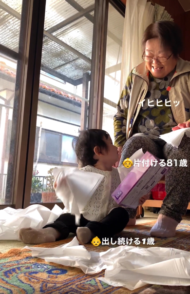 ティッシュで遊ぶ赤ちゃんを見守るひいおばあちゃん