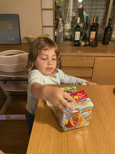 テーブルの上のふりかけに手を出す2歳児