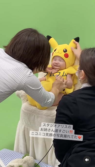 カメラマンが赤ちゃんをあやしている写真