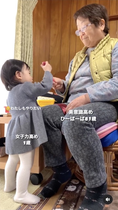 ひいおばあちゃんにローラーを借りる女の子の写真