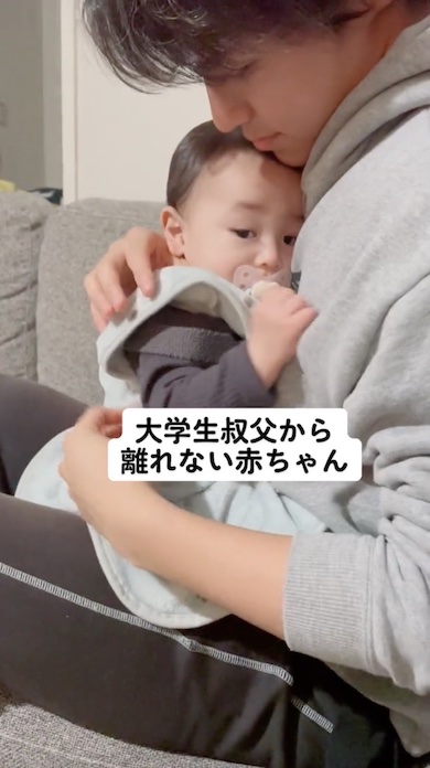 大学生の叔父が赤ちゃんを縦だっこしている写真