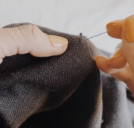 針をほつれた糸に絡めながら