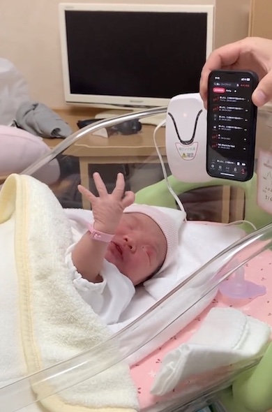 左手を掲げる新生児の写真