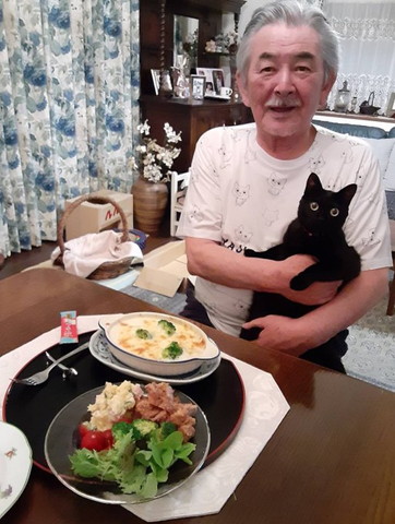 白いTしゃつでグラタンを前に猫を抱っこ