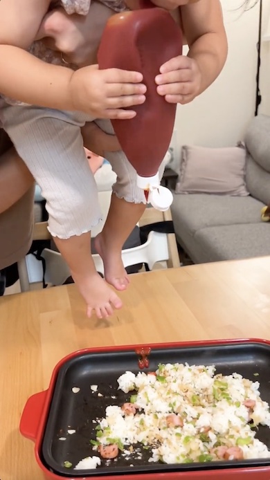 抱き上げられた状態でケチャップをさす女の子の写真