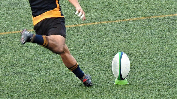 ラグビーボールとそれを蹴る人の画像