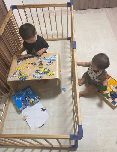 ベビーサークルの中で遊ぶお兄ちゃんと、外で遊ぶ赤ちゃんの画像