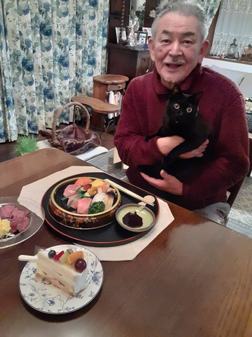 寿司を前にしたお父さんと猫