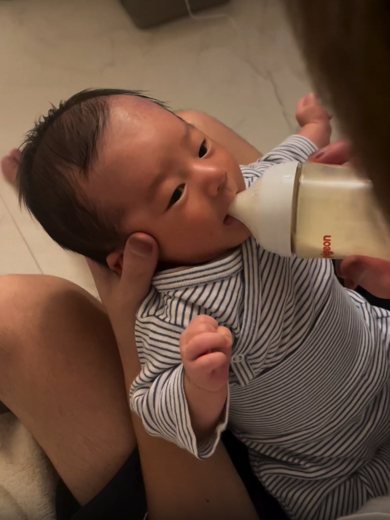 うきうきで哺乳瓶をくわえる赤ちゃん