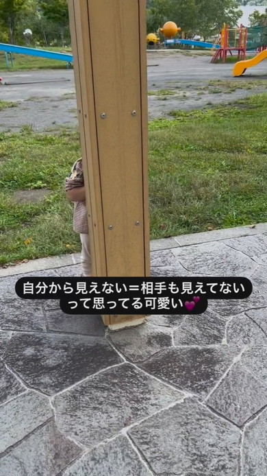 柱の後ろにかくれる2歳の女の子