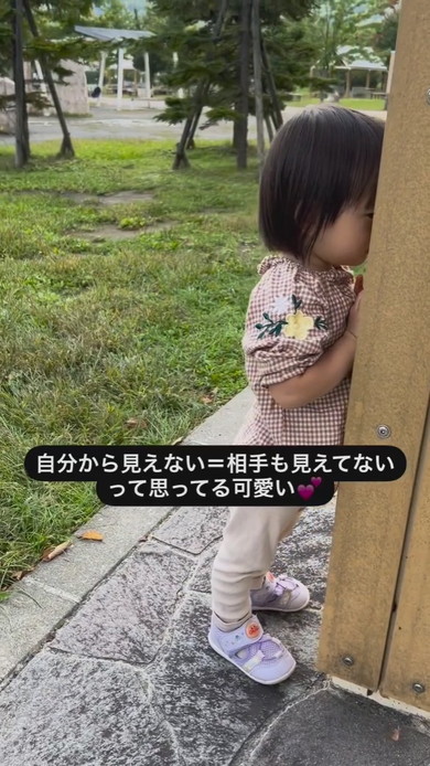柱の後ろにかくれる2歳の女の子