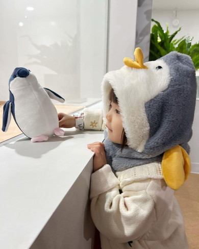 ペンギンのフードをかぶる2歳の女の子