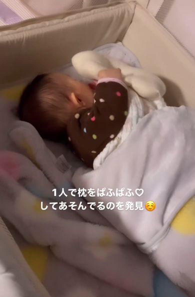 枕を自分のほっぺにぱふぱふして遊ぶ赤ちゃん
