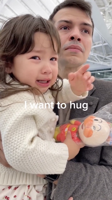 父に抱かれ手を伸ばして泣いている女の子