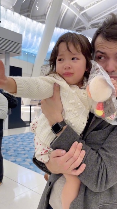 父に抱かれ手を振って泣いている女の子