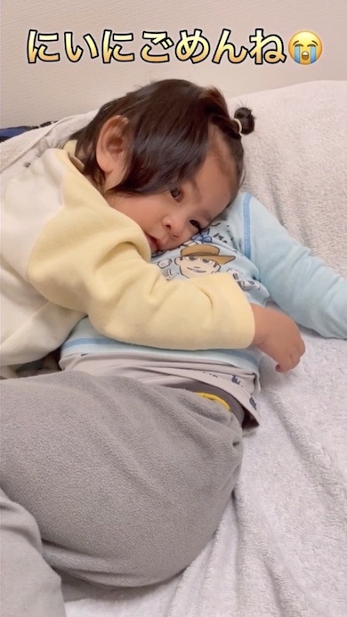 寝ている兄に抱きついている1歳の女の子