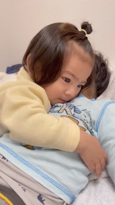 寝ている兄を抱きしめる1歳の女の子