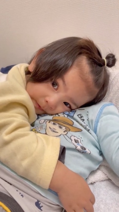 寝ている兄に抱きついている1歳の女の子