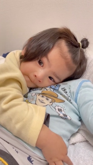 寝ている兄に抱きついている1歳の女の子