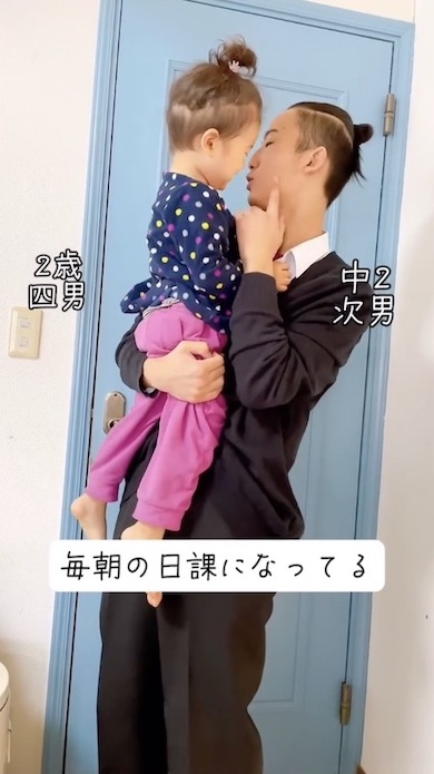 中2の兄が2歳弟を抱き自分の左頬を指さしている