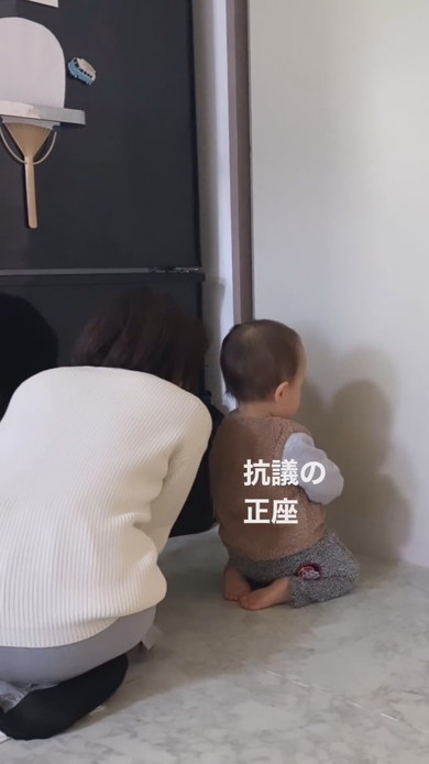 すねて正座し壁を向いている1歳児