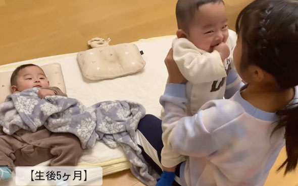 双子の赤ちゃんをあやす9歳の姉