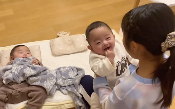 双子の赤ちゃんをあやす9歳の姉