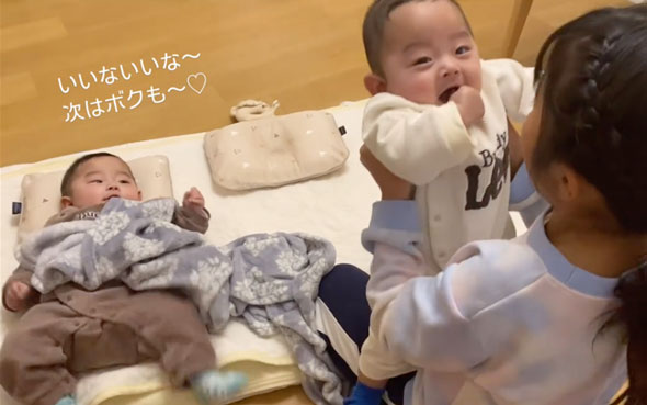 双子の赤ちゃんをあやす9歳の姉
